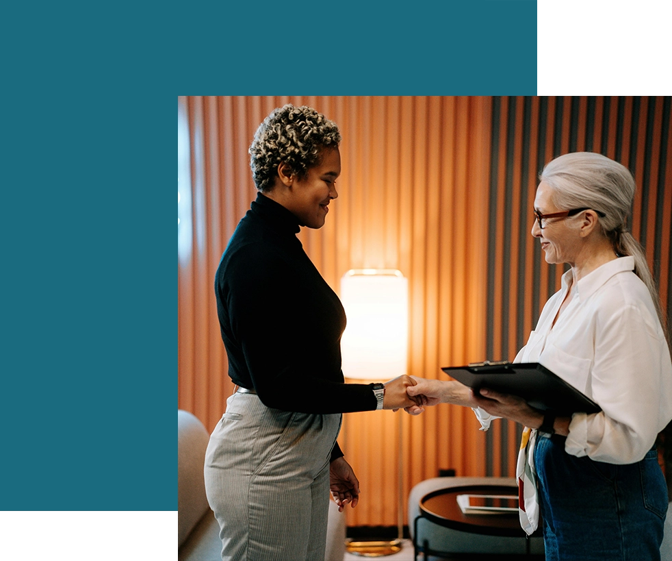 Two women shaking hands in a room.