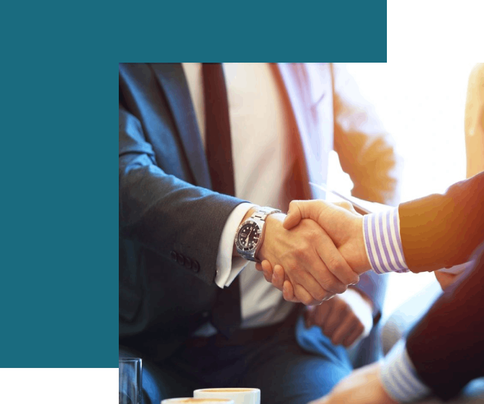 Two people shaking hands over a table.